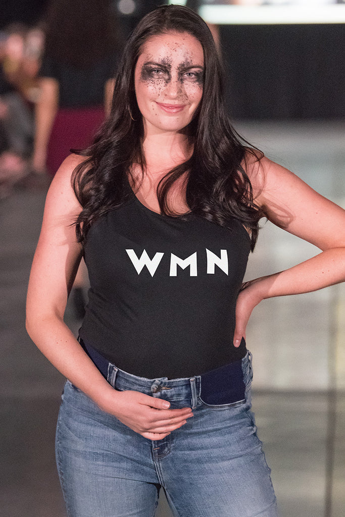 A white pregnant woman wearing a black tank top and maternity jeans