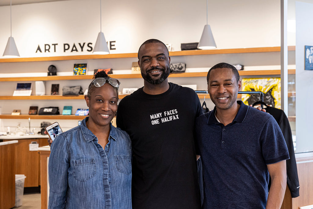 Duane poses with family while wearing the Many Faces One Halifax Tee at Halifax Shopping Centre during an Art Pays Me and HaliTube pop-up event. Photo by Emma Lomas.