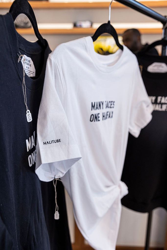 Many Faces One Halifax Tee, White on a hanger at Halifax Shopping Centre. Photo by Emma Lomas.